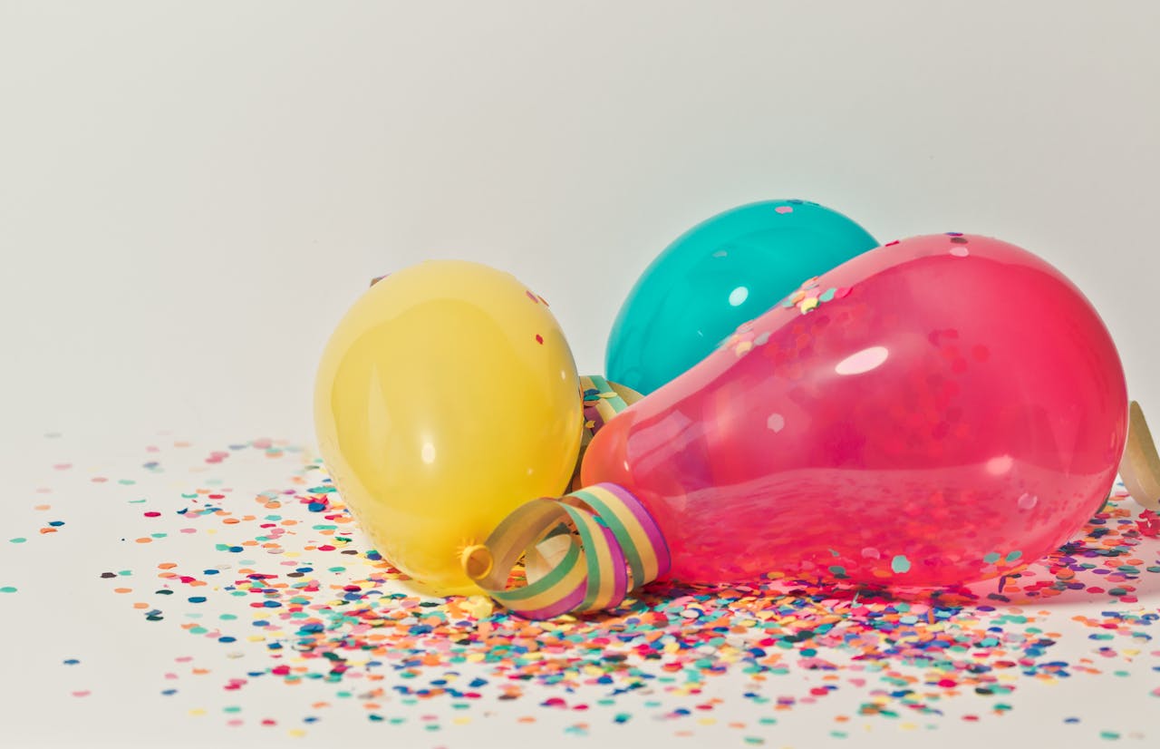 Vibrant colorful balloons surrounded by confetti, perfect for party celebrations.