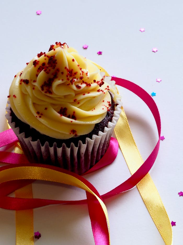 services-03 Tempting chocolate cupcake with creamy icing, adorned with colorful ribbons and confetti for a festive celebration.
